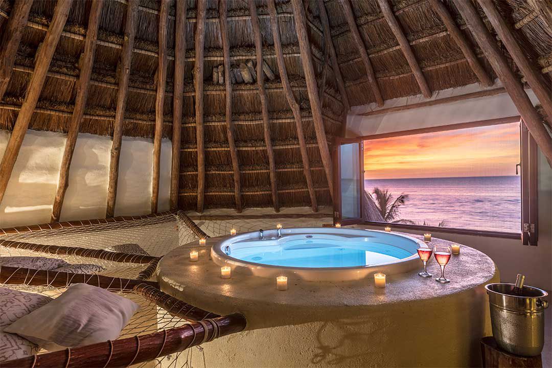 une hamac et un jacuzzi installés sous une palapa dans ce bungalow privé au Mexique