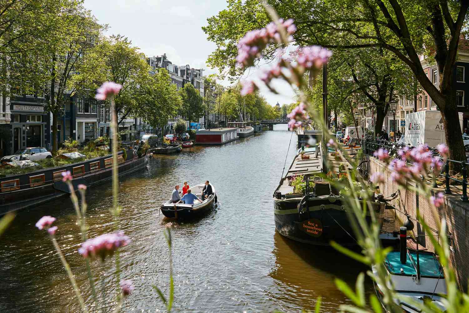 Un bateau sur le canal Prinsengracht d'Amsterdam, vu à travers la verdure sur la rive