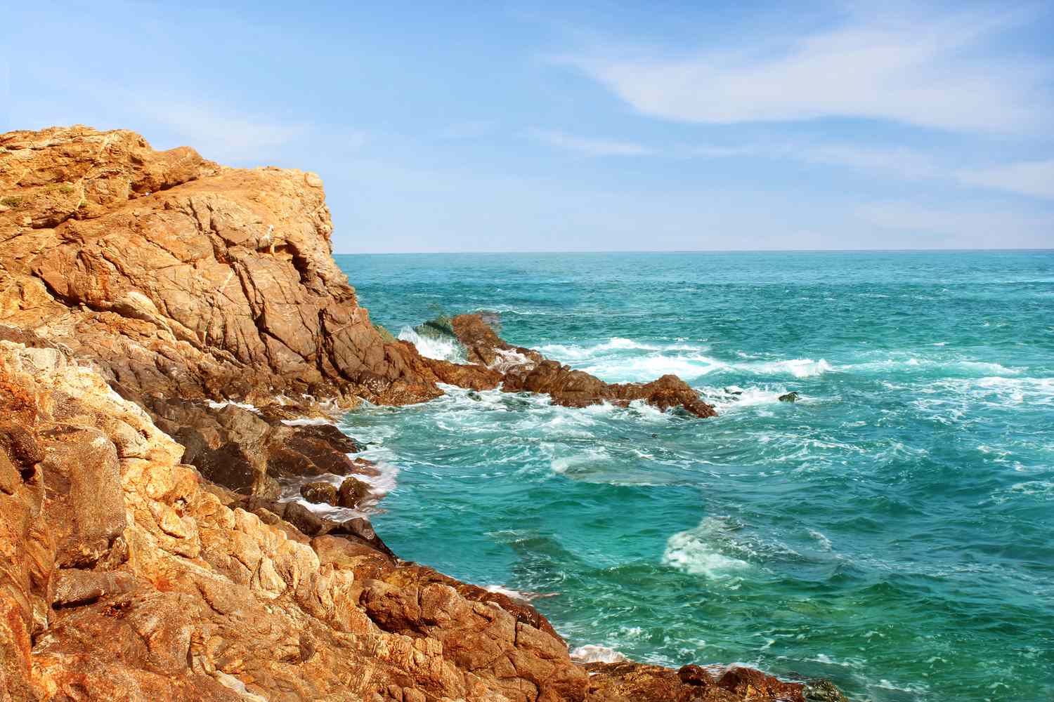 Côte rocheuse et accidentée d'Oaxaca, Mexique. Orientation horizontale pour un arrière-plan avec des rochers, une eau agitée et un ciel bleu clair.