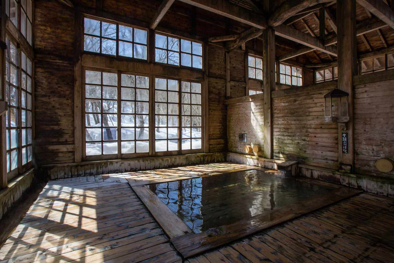 Onsen intérieur avec de grandes fenêtres donnant sur la neige