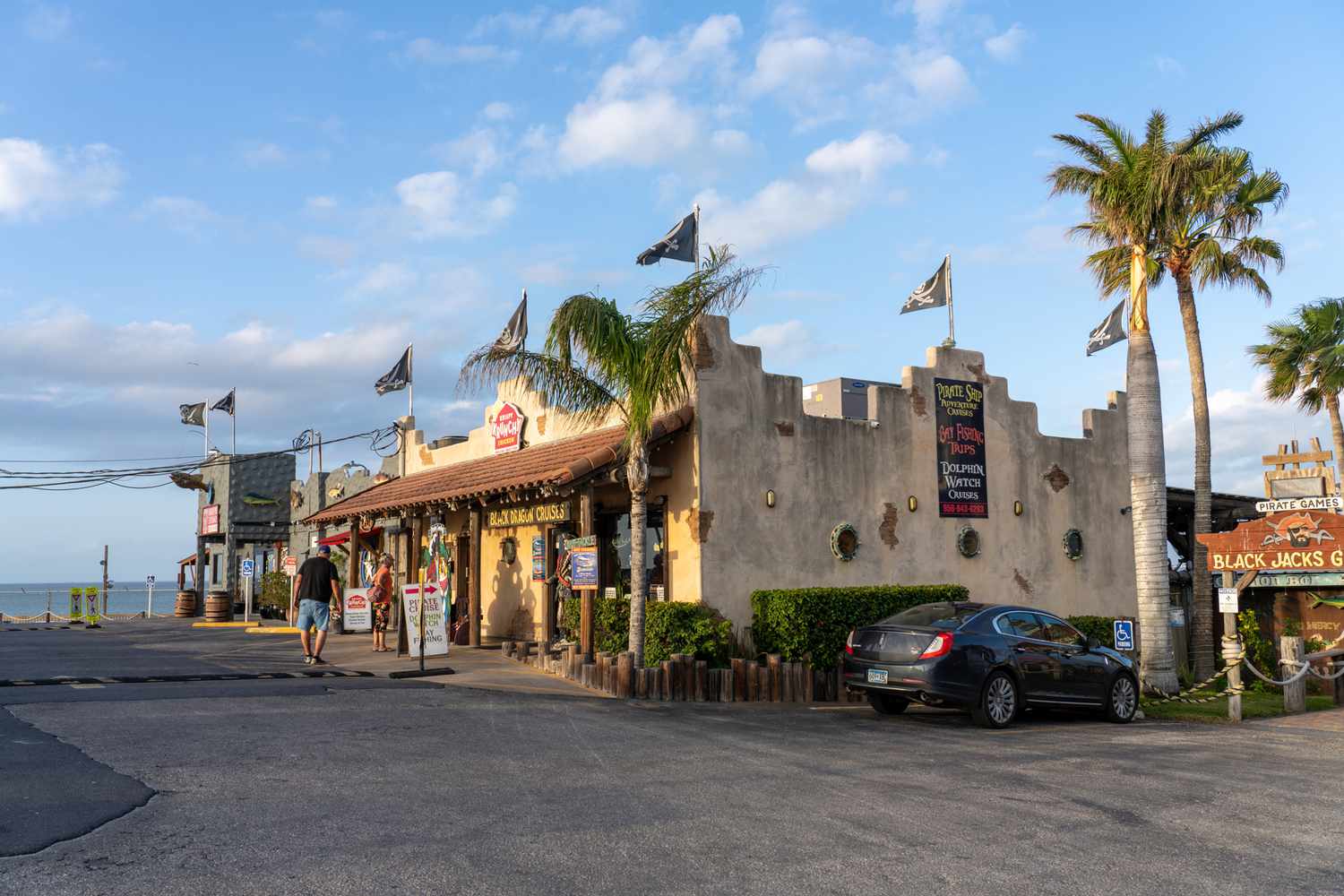 Un magasin de souvenirs et un bureau de visites en bateau avec des drapeaux de pirate près de la Laguna Madre à Port Isabel, Texas. Deux touristes âgés se tiennent devant.