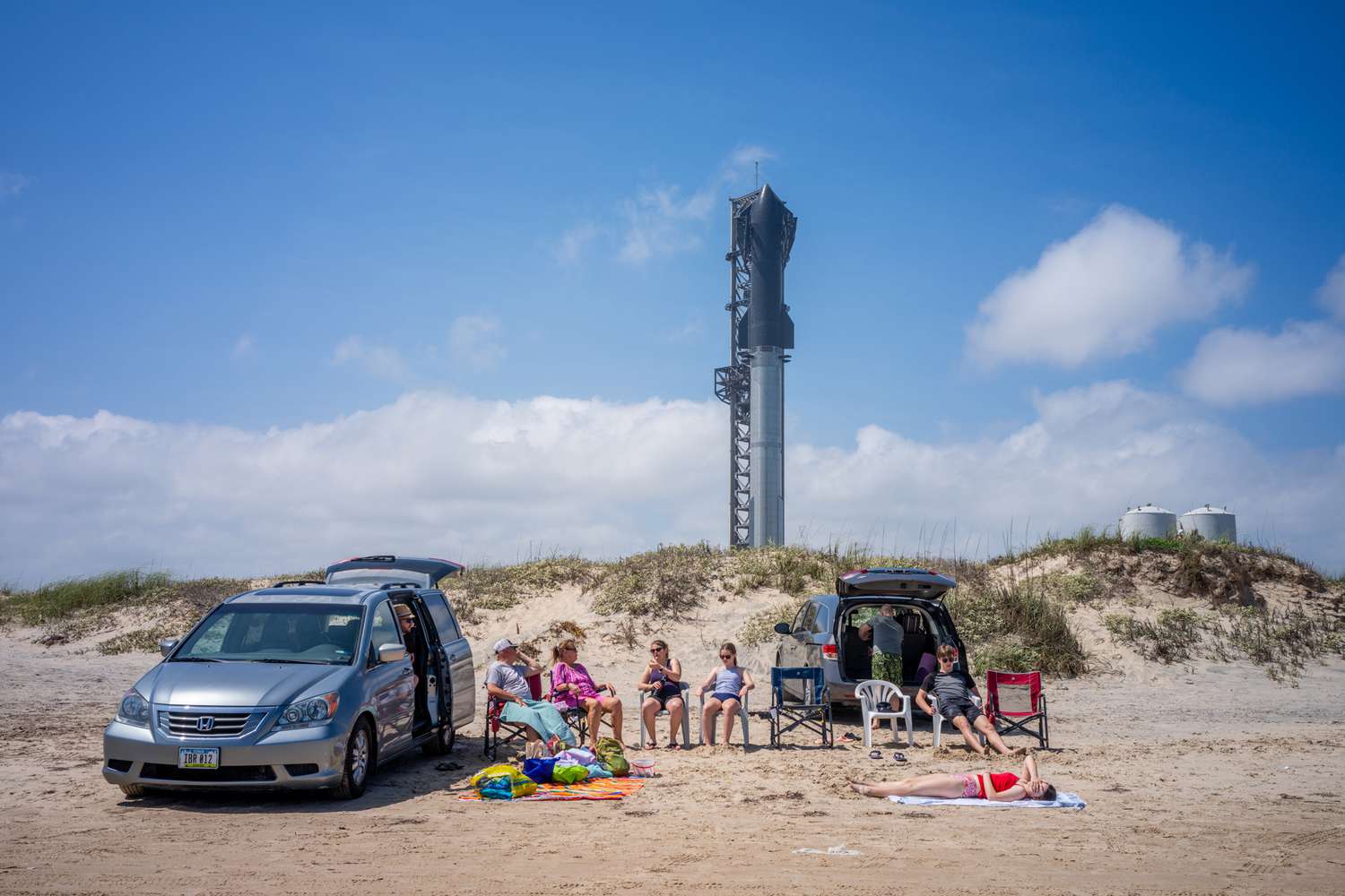 Des gens passent du temps sur la plage près de la fusée Starship Flight 3 un jour avant son lancement prévu au complexe Starbase près de Boca Chica beach