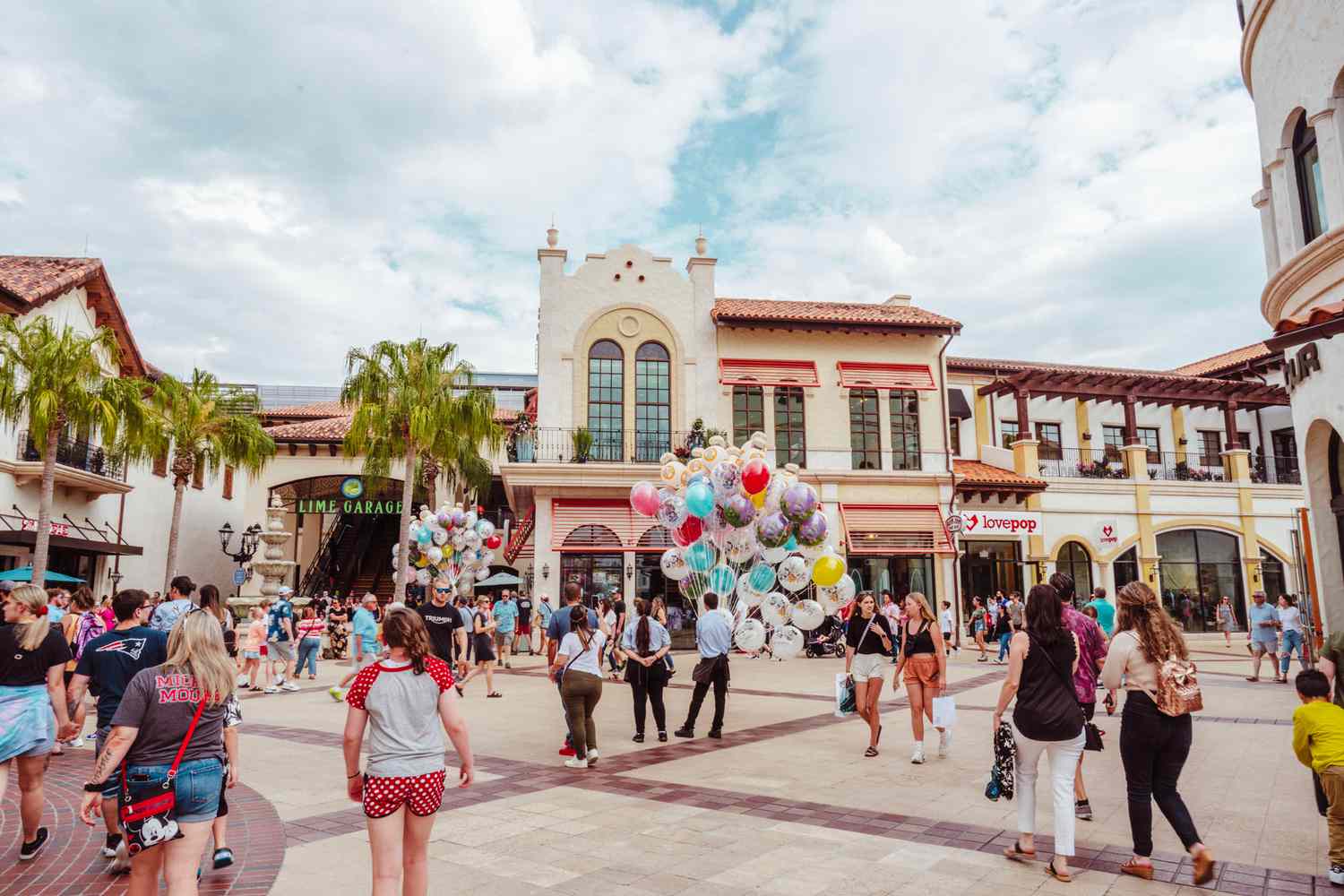 Foule importante entrant à Disney Springs avec un homme tenant un gros lot de ballons