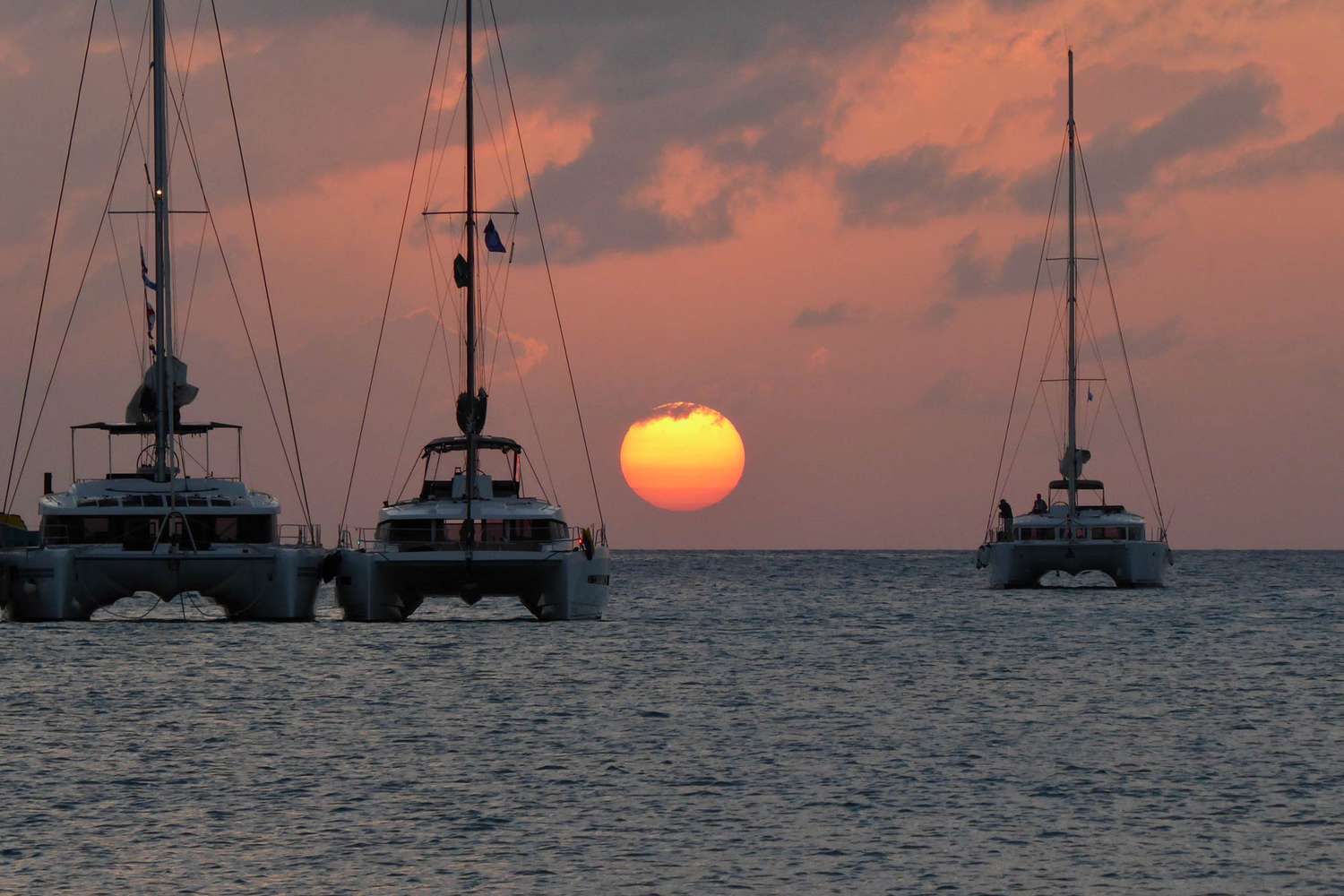 Le soleil se rapproche de l'horizon dans cette scène de coucher de soleil avec des catamarans sur l'eau près d'Anguilla.