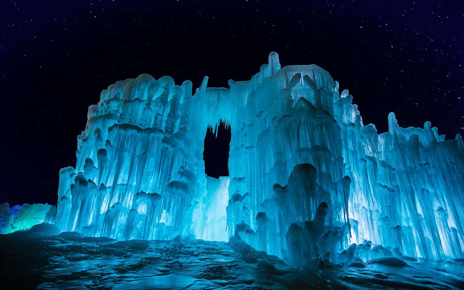 One of New Hampshire's Ice Castles glows blue against a dark night sky