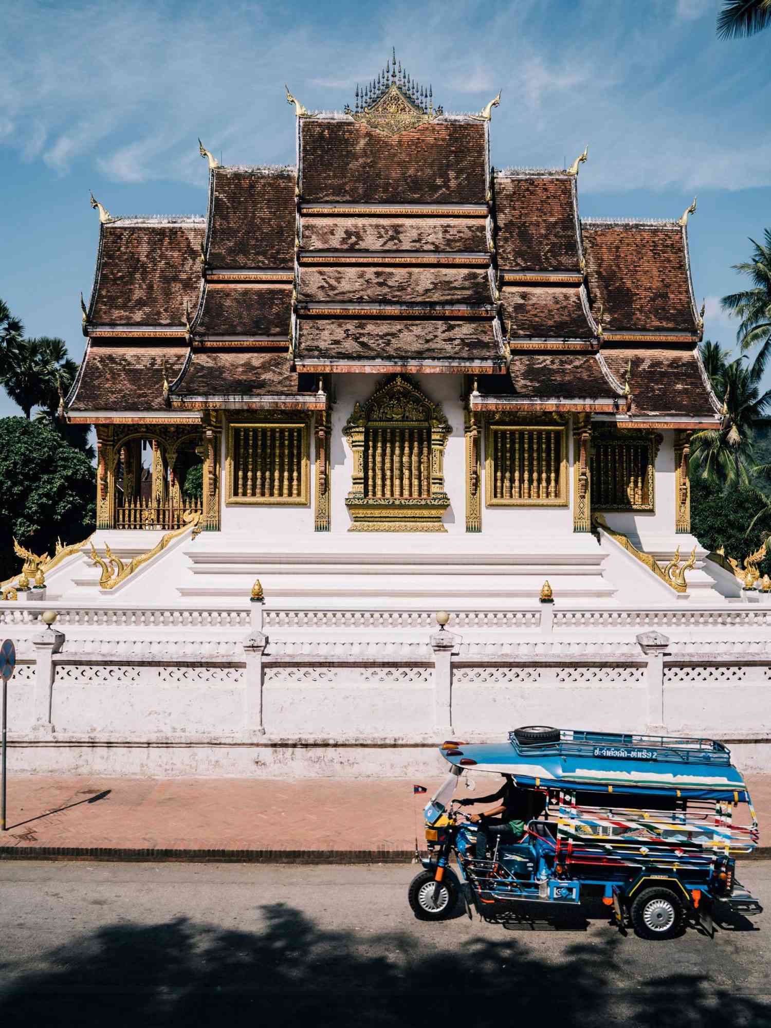 Scènes d'une croisière sur le Mékong : un taxi bleu devant un temple à Luang Prabang, Laos