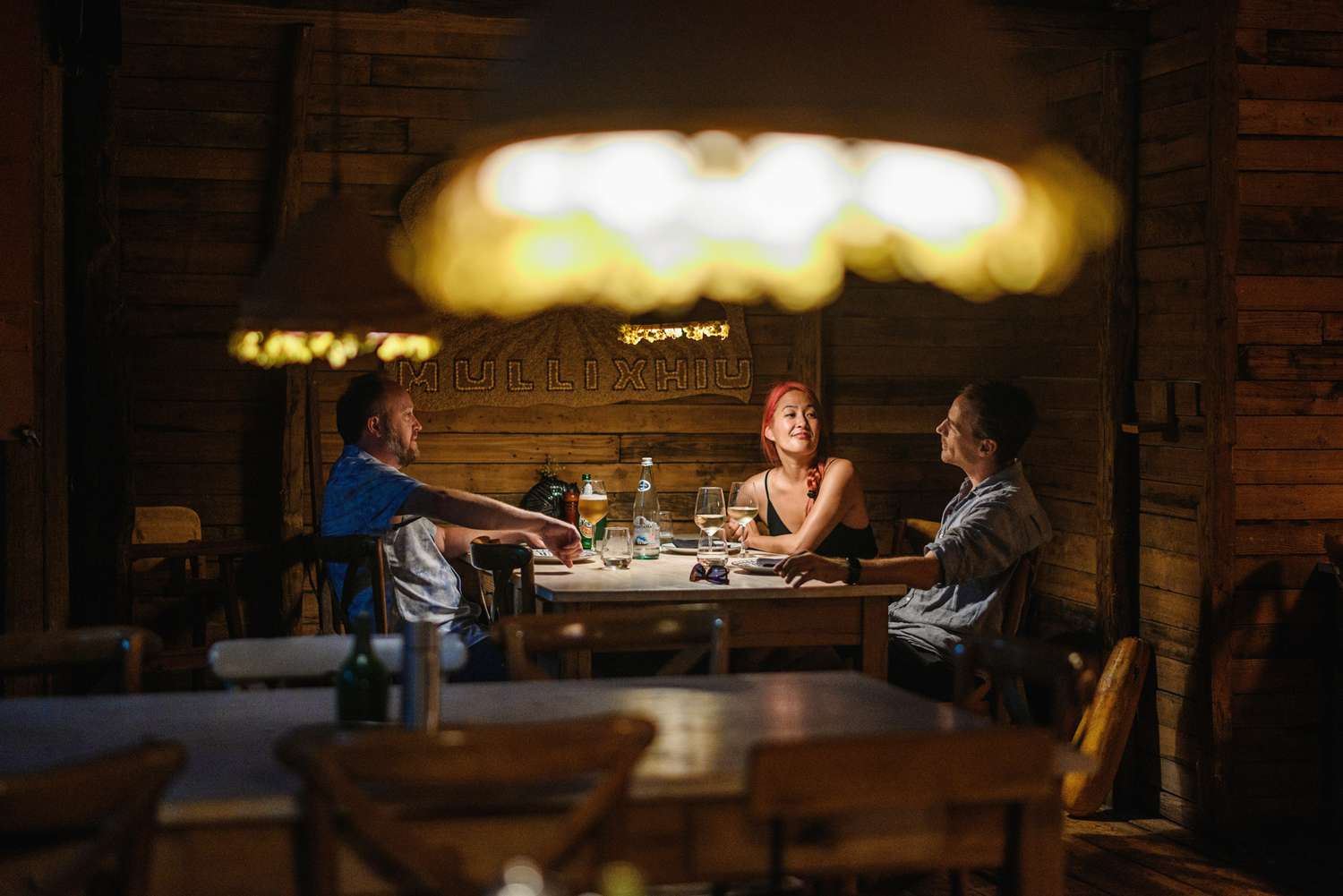 Vue d'un restaurant tamisé, avec trois dîneurs à une table