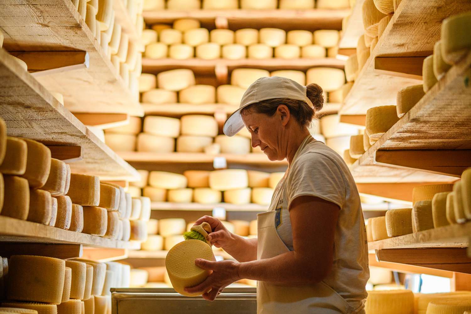 Une femme nettoyant un fromage dans une cave à fromage