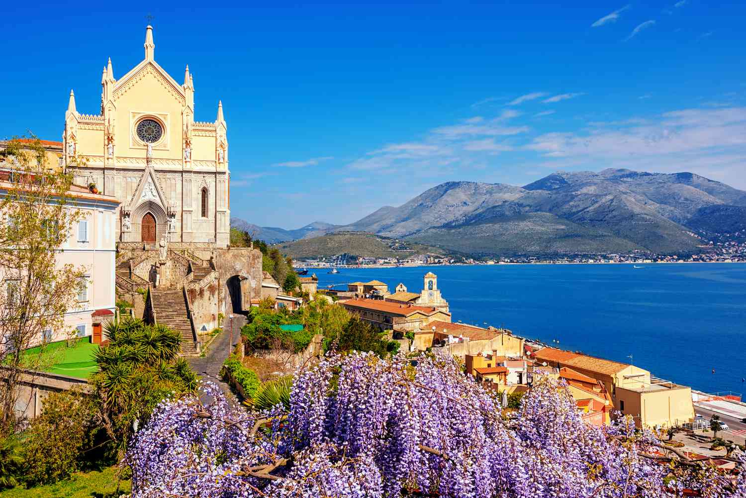 Gaeta, Italie, fleurs de glycine en fleur et églises historiques de Saint François d'Assise et de Santissima Annunziata sur les eaux bleues de la baie de Gaeta