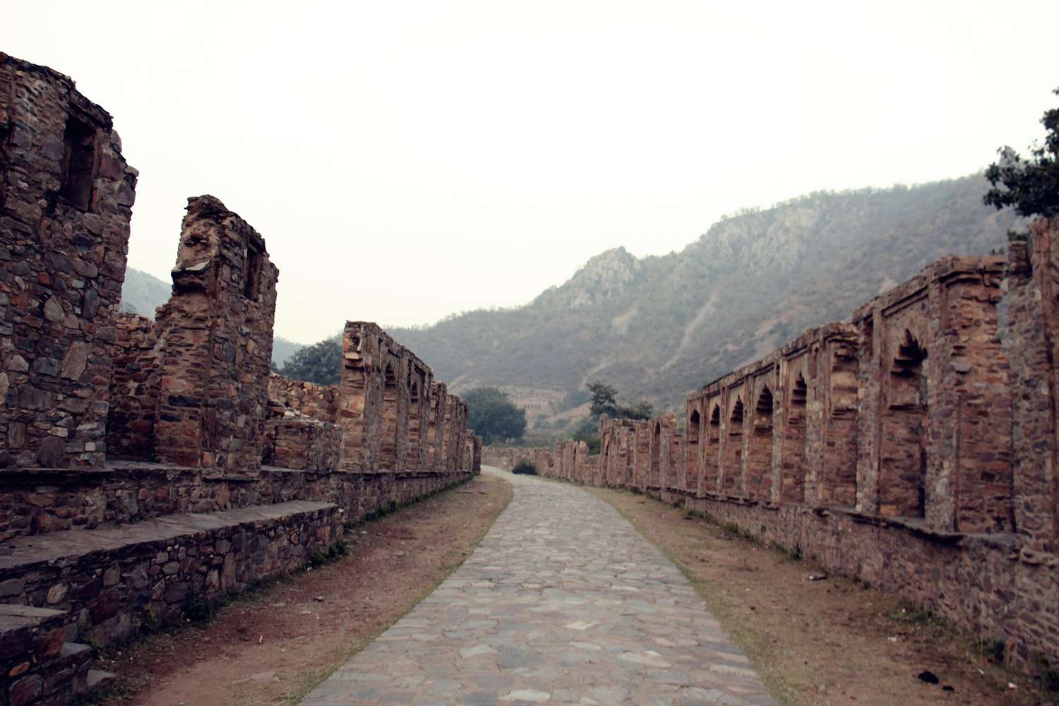 Sentier traversant des ruines par un jour de brume inquiétante