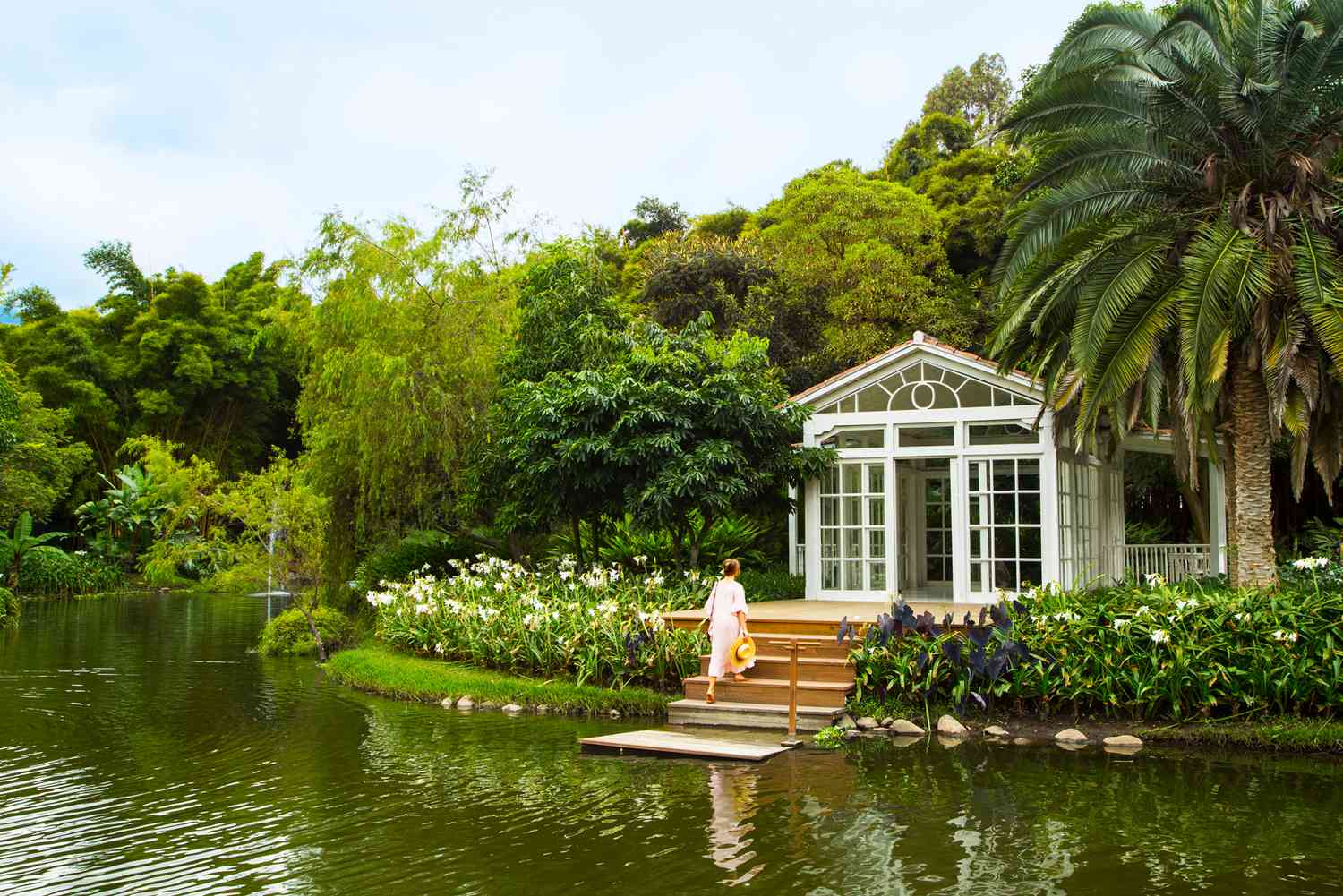 Une serre au bord de l'eau dans le jardin d'un hôtel, avec une femme montant les marches
