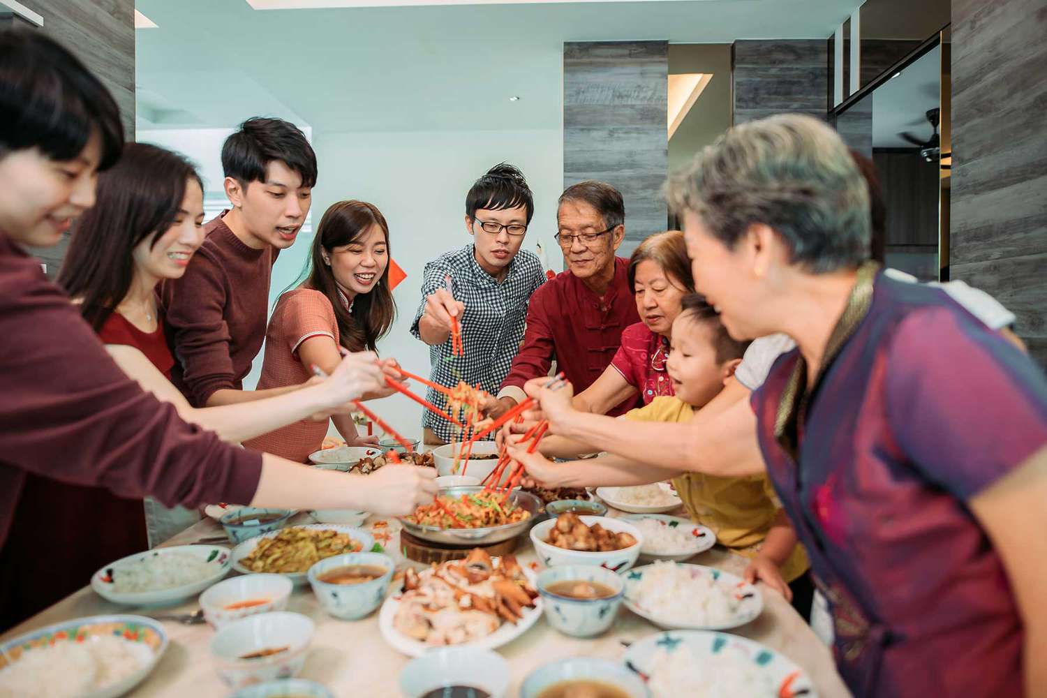 Famille célébrant la veille du Nouvel An lunaire avec une salade de poisson cru Lou Shang lors du dîner de retrouvailles.
