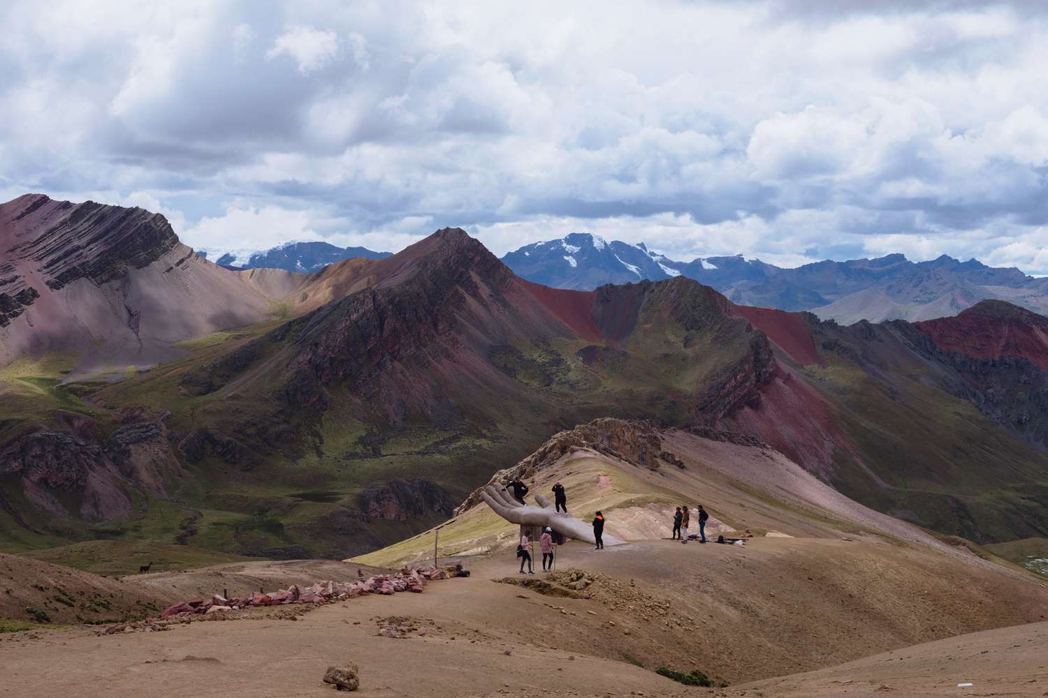 Randonneurs devant une statue de main près de la Montagne Arc-en-Ciel