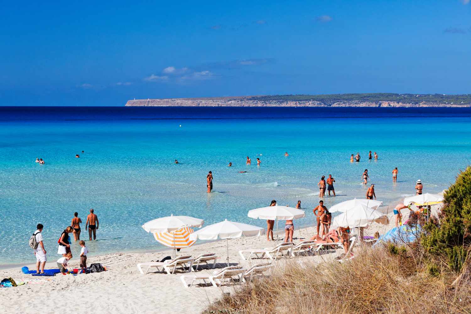 Des gens sur le sable et dans les eaux claires de la plage de Migjorn
